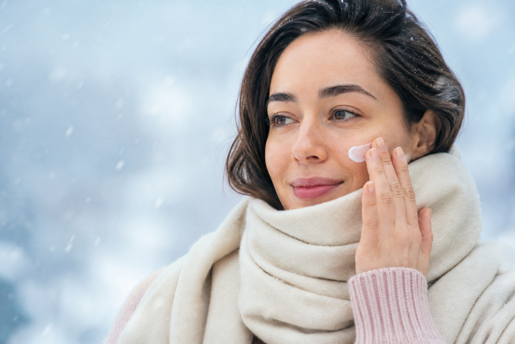 Woman applying moisturizer before protecting her face from cold winter wind